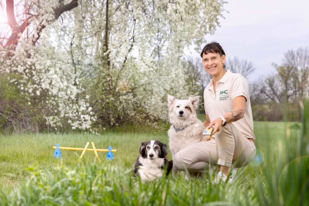 Kathi Till mit zwei Hunden auf einer Wiese beim Bewegungstraining